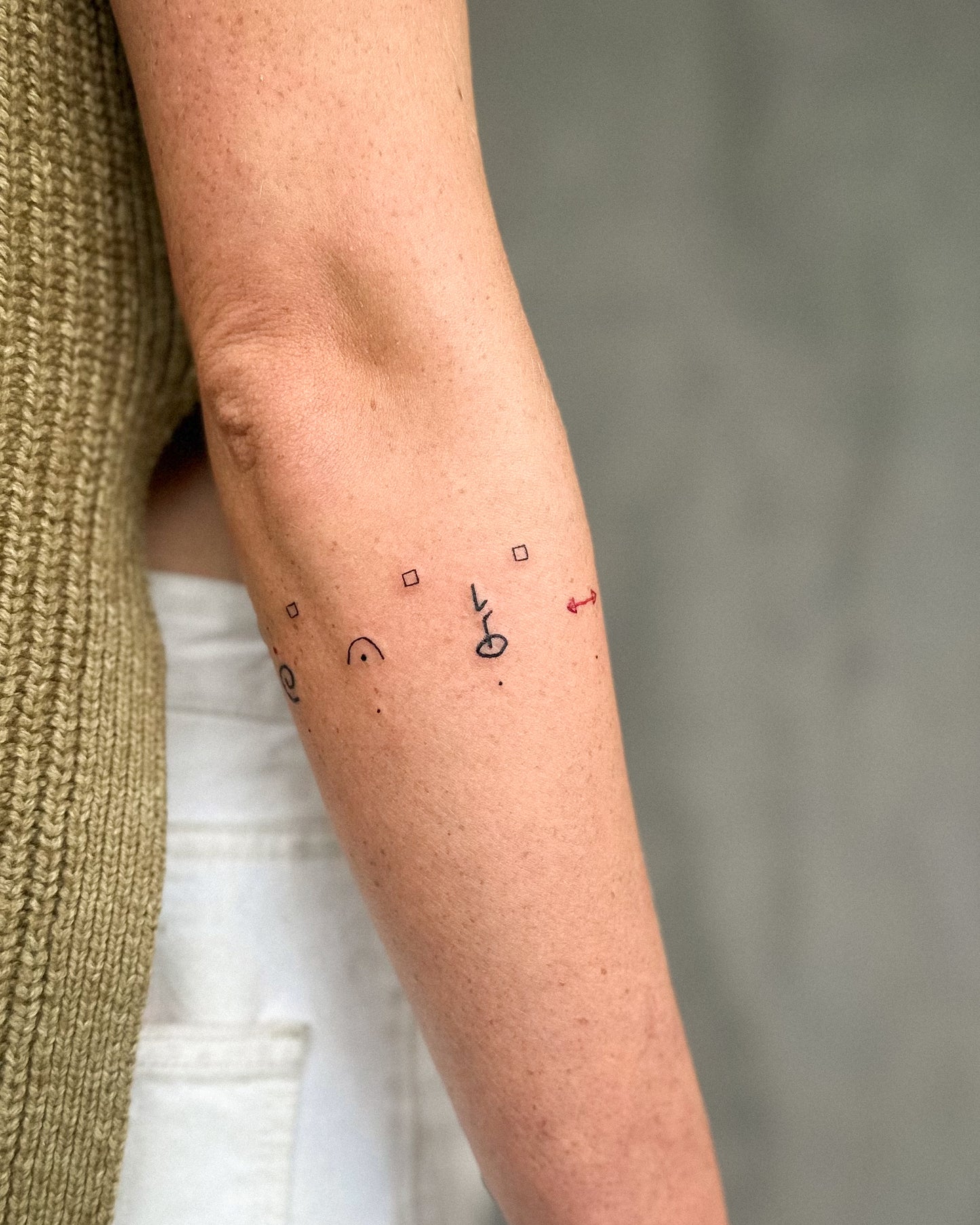 Outer Forearm view of wrap around symbols abstract cave painting paleolithic tattoo design by Eli inking in Bristol