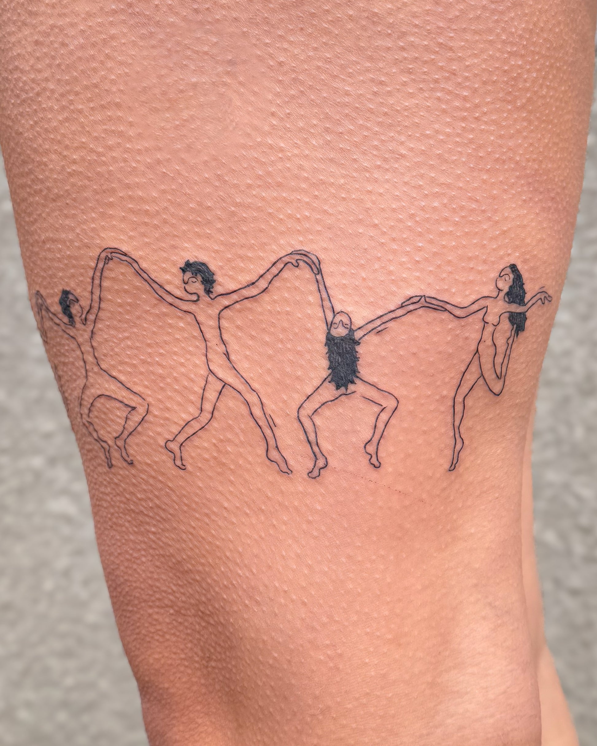 Tattoo of Figures dancing around a thigh wrapping all the way around and holding hands in linework style 