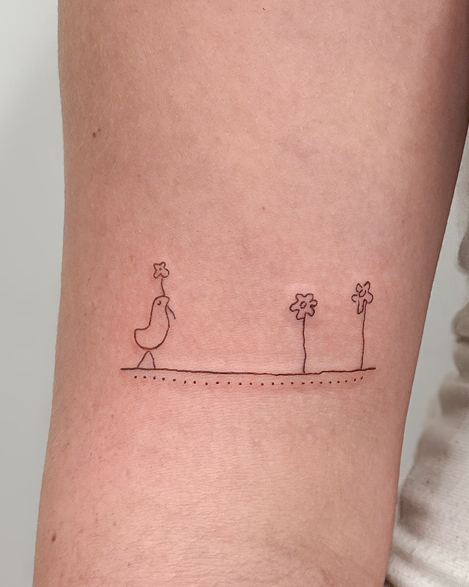 Fine line tattoo of a little bird and two flowers standing on a single line, on the upper arm, by Eli Inking in Bristol