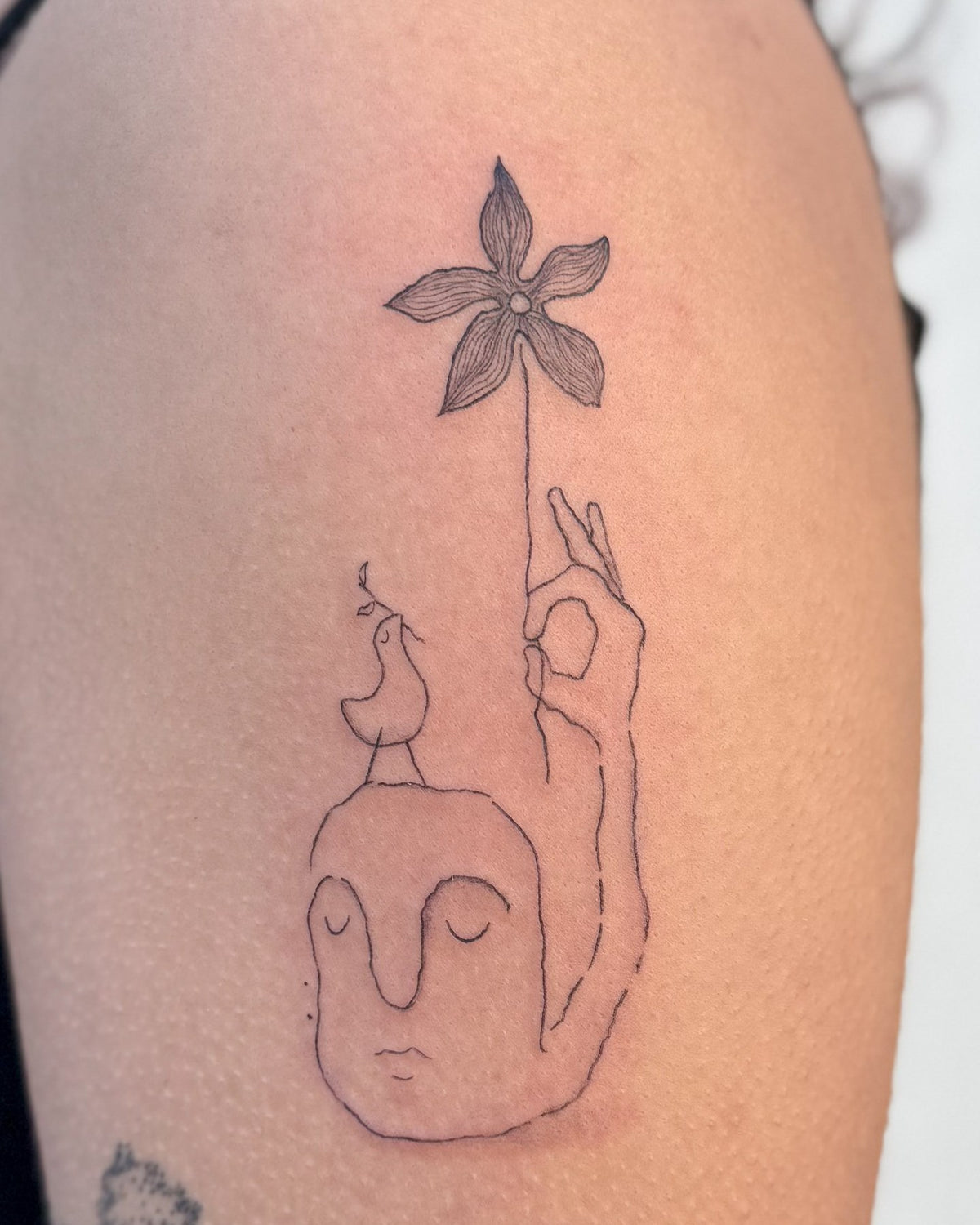 Fine line tattoo of a face beside a tall hand holding up a flower, on the upper arm, by Eli Inking in Bristol