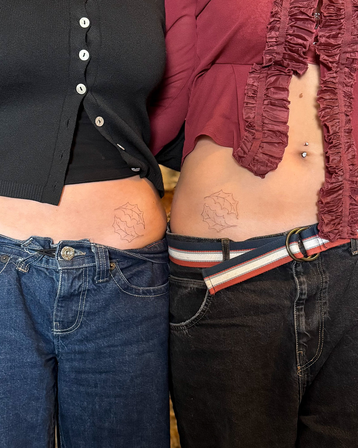Two friends with matching small fine line spiky sun tattoos on the hip, by Eli Inking in Bristol