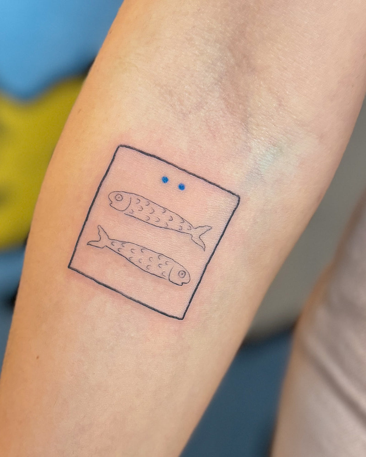 Fine line tattoo of two fish inside a square box, on the forearm, by Eli Inking in Bristol