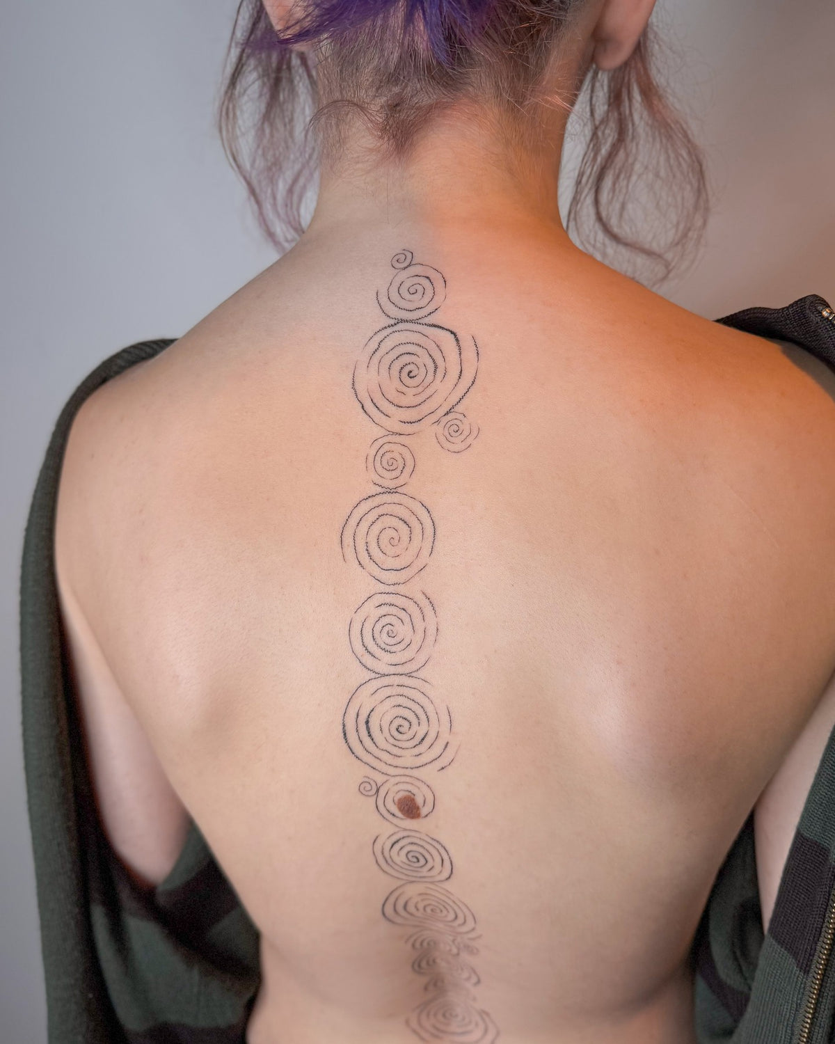 Spine tattoo of fine line spirals running from the neck down the back, by Eli Inking in Bristol