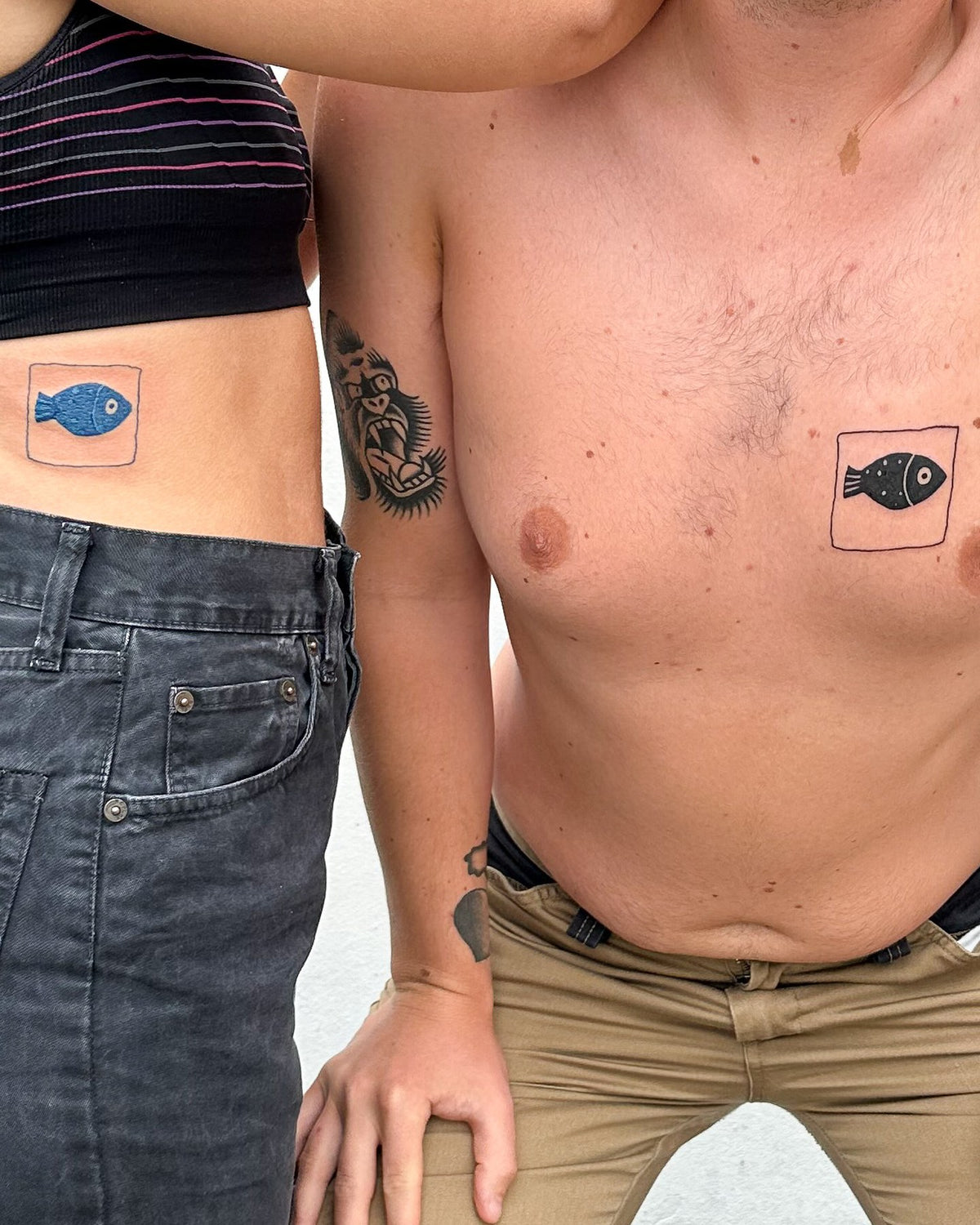 Matching fish tile tattoos, one blue fish and one black fish, on two people, by Eli Inking in Bristol