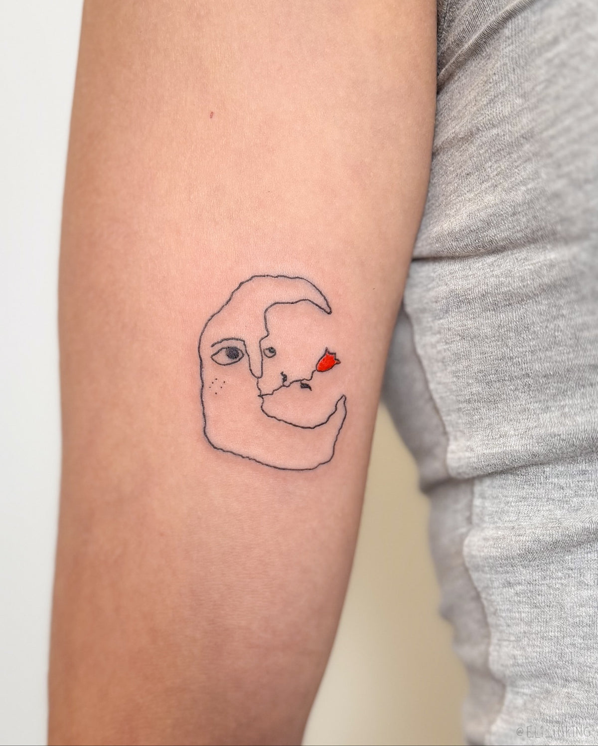 Fine line crescent moon face tattoo with a small red flower, on the arm, by Eli Inking, Bristol