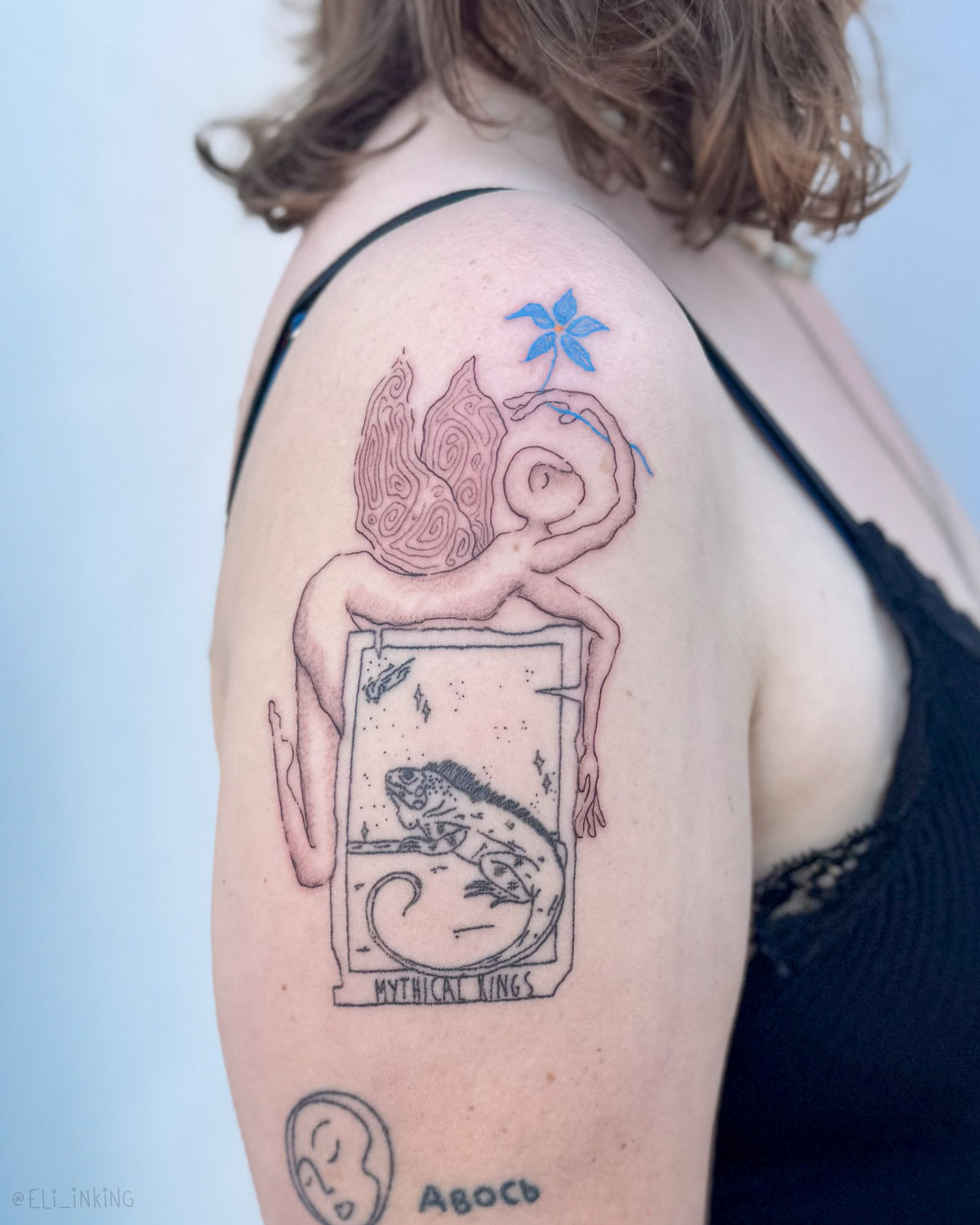 Figure and flower tattooed beside an existing tarot card tattoo on a shoulder