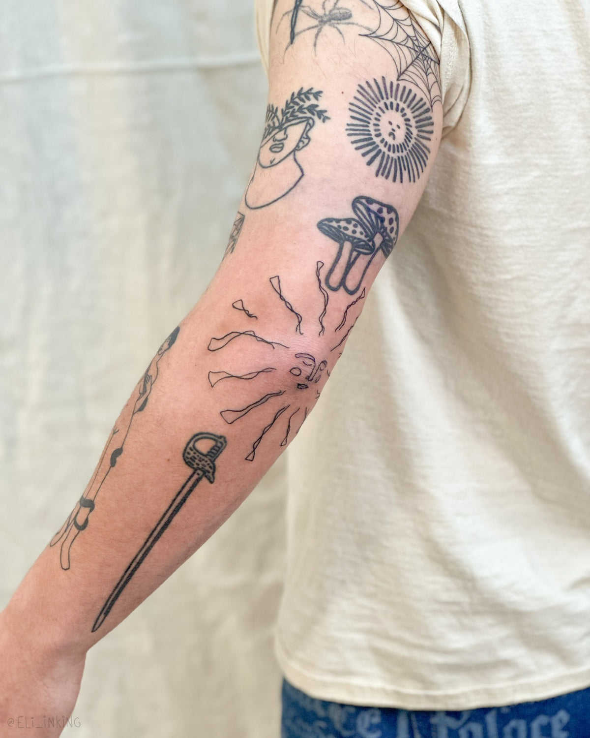 Patchwork sleeve with a freehand sunshine at the elbow, its rays connecting the surrounding tattoos