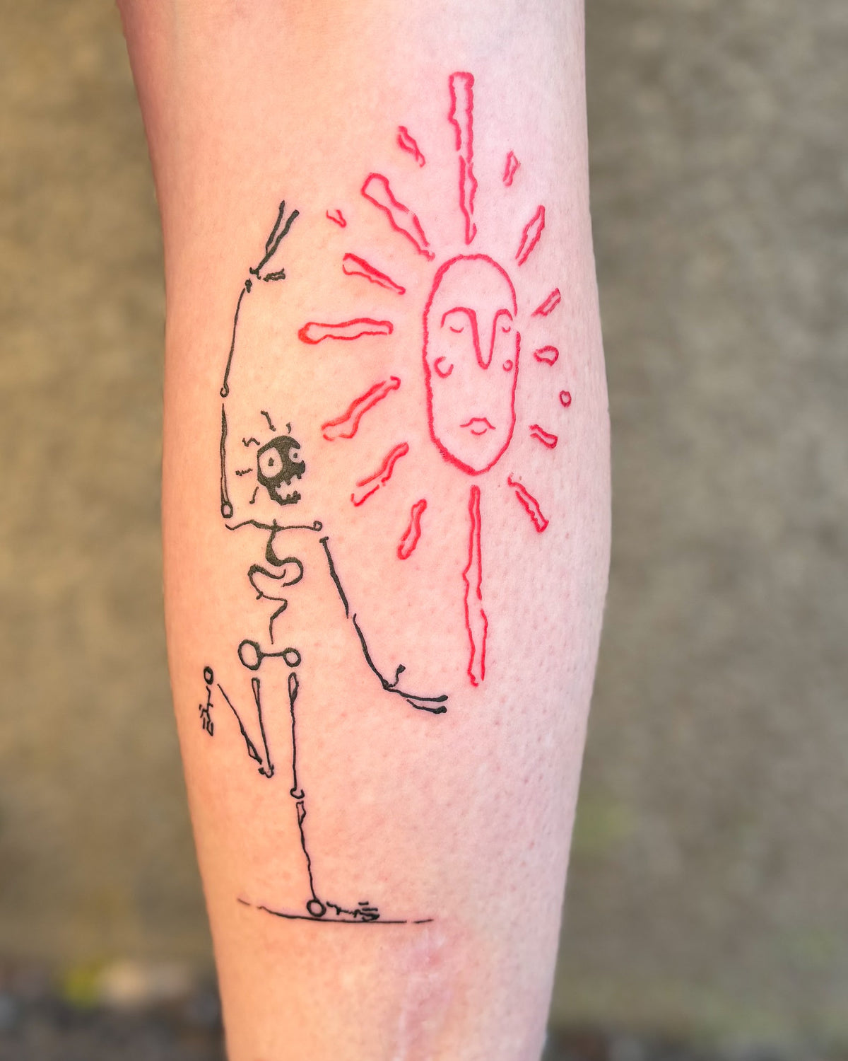A fine line skeleton tattoo reaching up beside a big red sun with a face, on a calf, by Eli Inking
