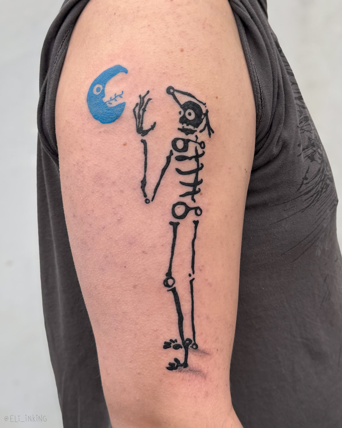 Skeleton reaching for a blue moon tattoo on the upper arm, by Eli Inking, Bristol