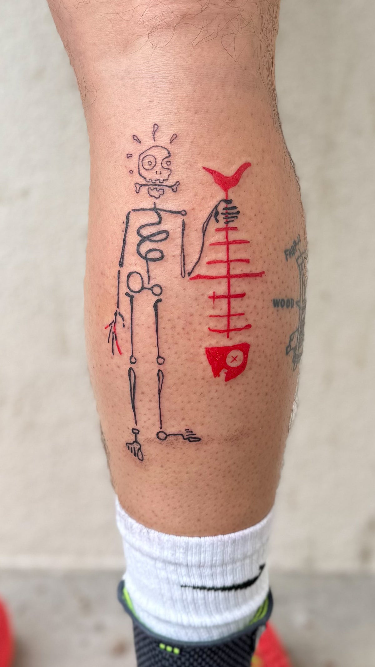 Fine line skeleton tattoo beside a big red fish skeleton, on a calf, by Eli Inking in Bristol