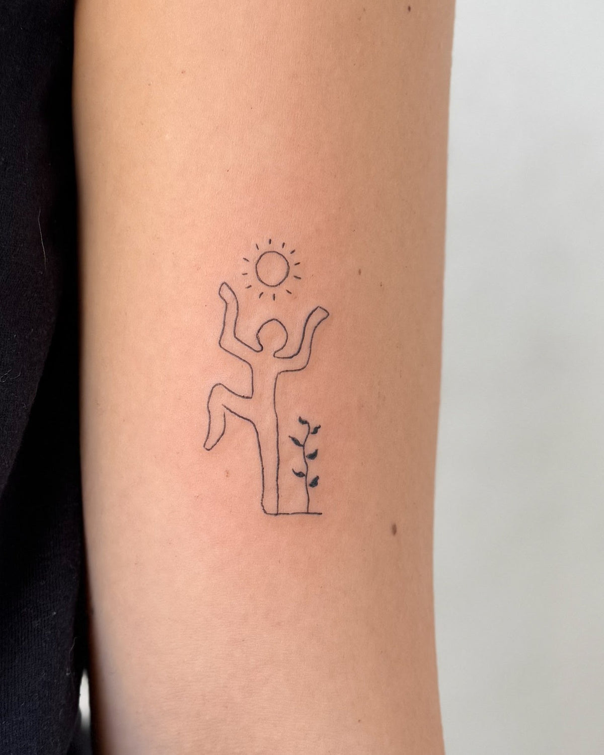Small fine line tattoo of a dancing figure under a little sun beside a plant, on the arm, by Eli Inking, Bristol