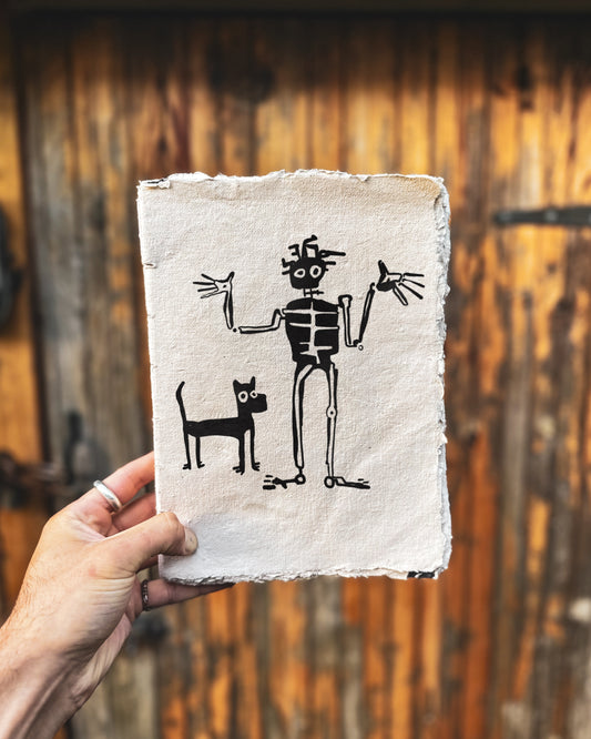 Bold drawing in black in of a skeleton shrugging and a dog beside him. The drawing is behind held in front of a wooden door. 
